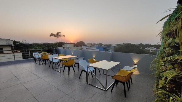 Terraza en la azotea con mesas y sillas, vista al atardecer y algunas plantas.