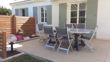 Relax on the patio with a round table and comfortable seating for six, surrounded by lush greenery and a charming garden view.