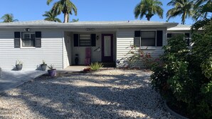 A single-story house with a gravel driveway, a purple door, and a mailbox.
