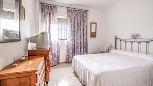 A bedroom with a bed, a wooden dresser, a television, a lamp, and curtains. - 3 bedroom awesome home in Matalascañas (Matalascañas)
