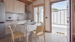 A kitchen with wooden cabinets, a dining table set for four, and a sliding glass door leading to an outdoor area. - 2 bedroom stunning home in Torrenova (Torrenova)