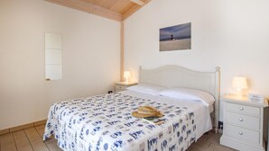 A bedroom with a bed, two bedside tables, a nightstand, a wall-mounted picture, and a ceiling with wooden beams. - 2 bedroom stunning home in Torrenova (Torrenova)