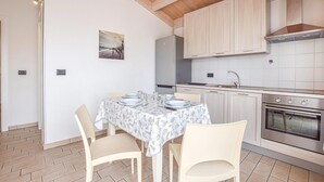 A kitchen with a dining table set for four, wooden cabinets, a stainless steel refrigerator, and a tiled backsplash. - 2 bedroom stunning home in Torrenova (Torrenova)