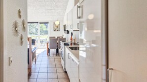 Eine moderne Küche mit weißen Schränken, einem Edelstahlkühlschrank und einem Essbereich mit Stühlen und einem Tisch.