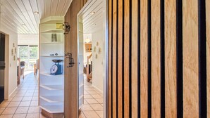 Ein Flur mit einer Wand aus Holzleisten, einer Waage und Blick in einen Essbereich.
