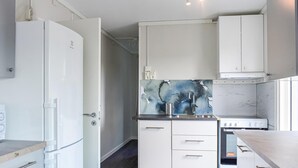 Moderni keittiö, jossa on valkoiset kaapit, sisäänrakennettu uuni ja ruostumattomasta teräksestä valmistettu pesuallas.