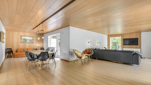 Un grand espace de vie comprenant une table à manger, des chaises, un canapé et un téléviseur.