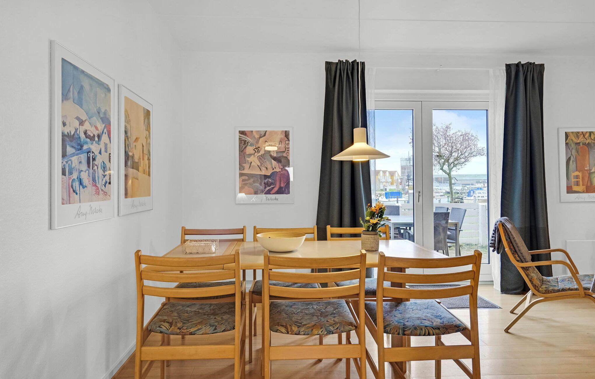 Un espace repas avec une table ronde, des chaises en bois et des œuvres d’art accrochées aux murs.