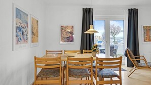 Ein Essbereich mit einem runden Tisch, Holzstühlen und Bildern an den Wänden.