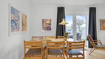 Un espace repas avec une table ronde, des chaises en bois et des œuvres d’art accrochées aux murs.