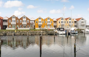 Casas coloridas em fileira, à beira de águas calmas com barcos atracados.