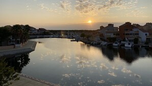 A marina with boats docked, a calm water body, and buildings in the background.
