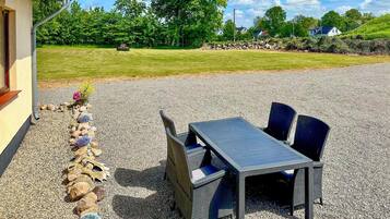 An outdoor seating area with a table and chairs, surrounded by a gravel path and a stone border.