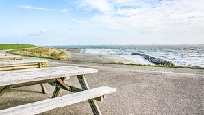A picnic table on a coastal road with a view of the ocean and a grassy area. - Lovely home in Heinkenszand with WiFi (Heinkenszand)