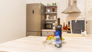 Una cocina con encimera de madera, una botella de vino, una copa y un bol de uvas.