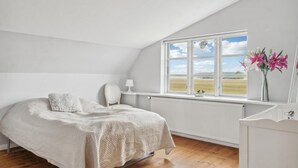 A bedroom with a bed, a chair, a window with a view of the countryside, and a radiator. - Nice home in Søllested with sauna (Søllested)