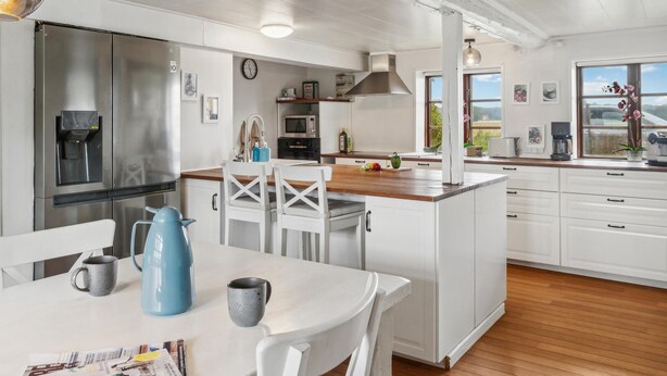 A modern kitchen with white cabinetry, stainless steel appliances, and a wooden island. - Nice home in Søllested with sauna (Søllested)