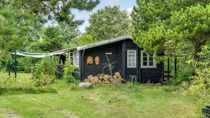 A rustic cabin with a thatched roof, surrounded by a dense forest. - Cozy home in Jægerspris with WiFi (Jægerspris)