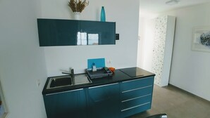 A modern kitchen with a black countertop, blue cabinets, and a built-in sink.