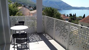 A balcony with a table and chairs, overlooking a lake and mountains.