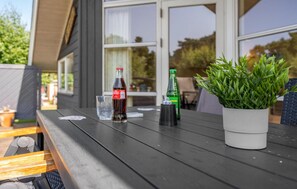 A wooden table with a bottle of dark soda, a glass, and a green bottle, along with a potted plant. - 2 bedroom cozy home in Gedser (Gedser)