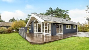 A modern house with a sloped roof, large windows, and a wooden deck.