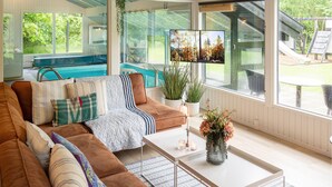 Una sala de estar moderna con un gran ventanal, una piscina y un tobogán a la vista.