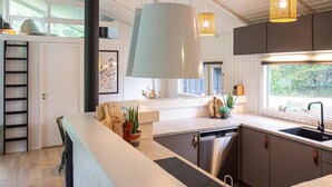 Una cocina moderna con lavavajillas, pileta y una lámpara colgante grande.