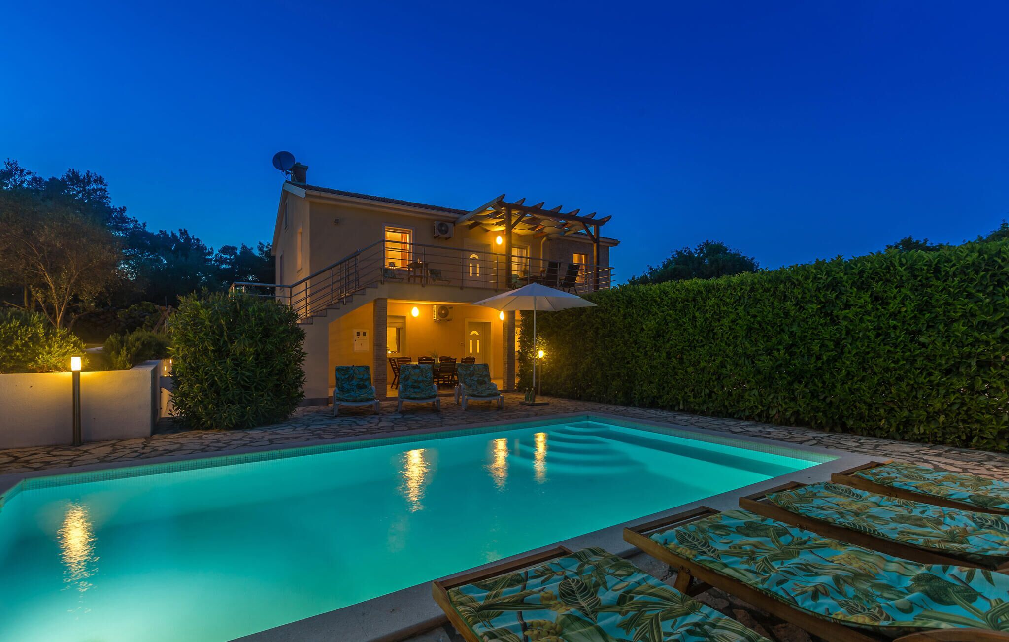 Une maison à deux étages dotée d’une piscine, d’un espace salon extérieur et d’un jardin bien entretenu.