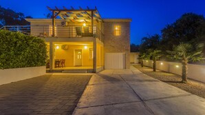 A two-story house with a balcony, a garage, and a well-lit entrance. - Holiday home with seaview (Vrh)