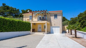 A two-story house with a balcony, a garage, and a paved driveway. - Holiday home with seaview (Vrh)