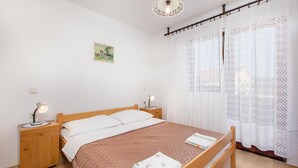 Une chambre à coucher avec un lit en bois, des rideaux blancs, une table de chevet avec une lampe et un tableau accroché au mur.