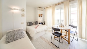Un dormitorio con cama, mesita de noche y una pequeña mesa con sillas.