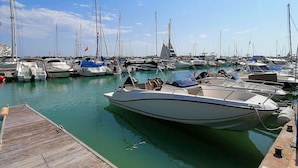 Un puerto deportivo con varios barcos amarrados, un muelle de madera y cielo despejado.
