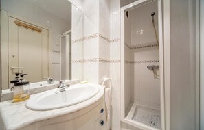 Une salle de bain avec un lavabo, un miroir et une douche.