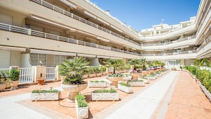 Un vestíbulo de hotel de varios niveles con balcones, plantas en macetas y un pasillo central.