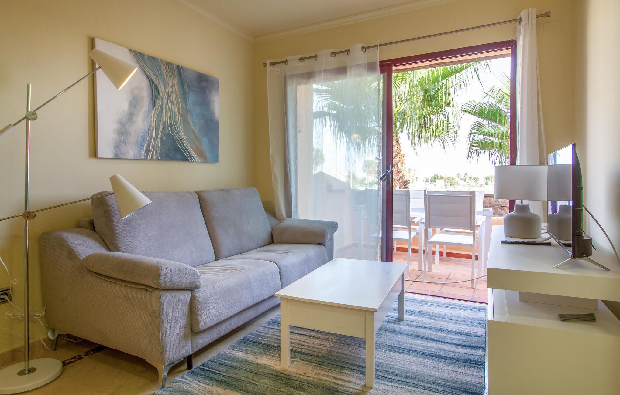 A modern living room with a sofa, a coffee table, a TV, and a painting on the wall.