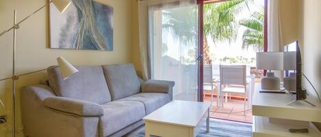 A modern living room with a sofa, a coffee table, a TV, and a painting on the wall.