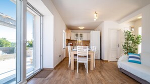 Een modern appartement met een eetgedeelte, keuken en woonkamer, inclusief een bank en een plant.