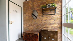Habitació amb paret de maó, una porta amb la inscripció 'Sala de Renteria', un mirall, prestatge amb plantes i dos mobles d'emmagatzematge metàl·lic.