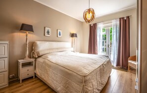 A bedroom with a large bed, bedside lamps, a dresser, and a view of the outdoors through a door. - Cozy apartment in Zoutelande with WiFi (Zoutelande)
