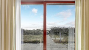 A view through a window with a red frame, looking out to a grassy area with a path leading to a body of water. - Beautiful home in Aakirkeby with WiFi (Aakirkeby)