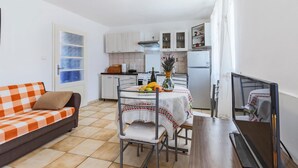 A compact living space with a kitchenette, a dining area with a table set for two, and a sofa with a checkered blanket. - 1 bedroom beautiful home in Pula (Pula)