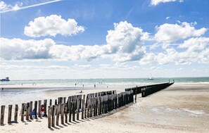 A beach with a wooden jetty, calm sea, and a sailboat in the distance. - Cozy apartment in Zoutelande with WiFi (Zoutelande)