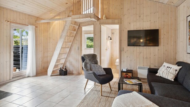 A spacious living area with a wooden interior, a staircase, a sofa, a chair, and a flat-screen TV. - 5 bedroom nice home in Hadsund (Hadsund)