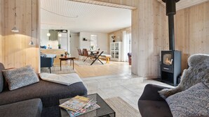 A cozy living room with a fireplace, a dining area, and a kitchen visible through an open door. - 5 bedroom nice home in Hadsund (Hadsund)