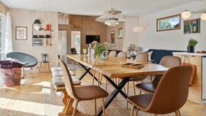 A spacious dining area with a long wooden table, multiple chairs, and a modern ceiling design. - 5 bedroom nice home in Hadsund (Hadsund)