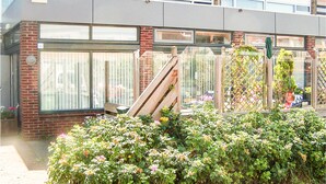 A building with large windows, a brick facade, and a garden area with various plants and flowers.