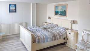 A bedroom with a bed, bedside tables, a chair, and a radiator.