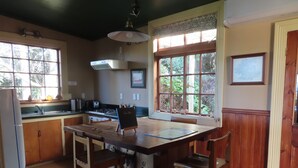 Una cocina con armarios de madera, una isla central con taburetes, una estufa y un fregadero.